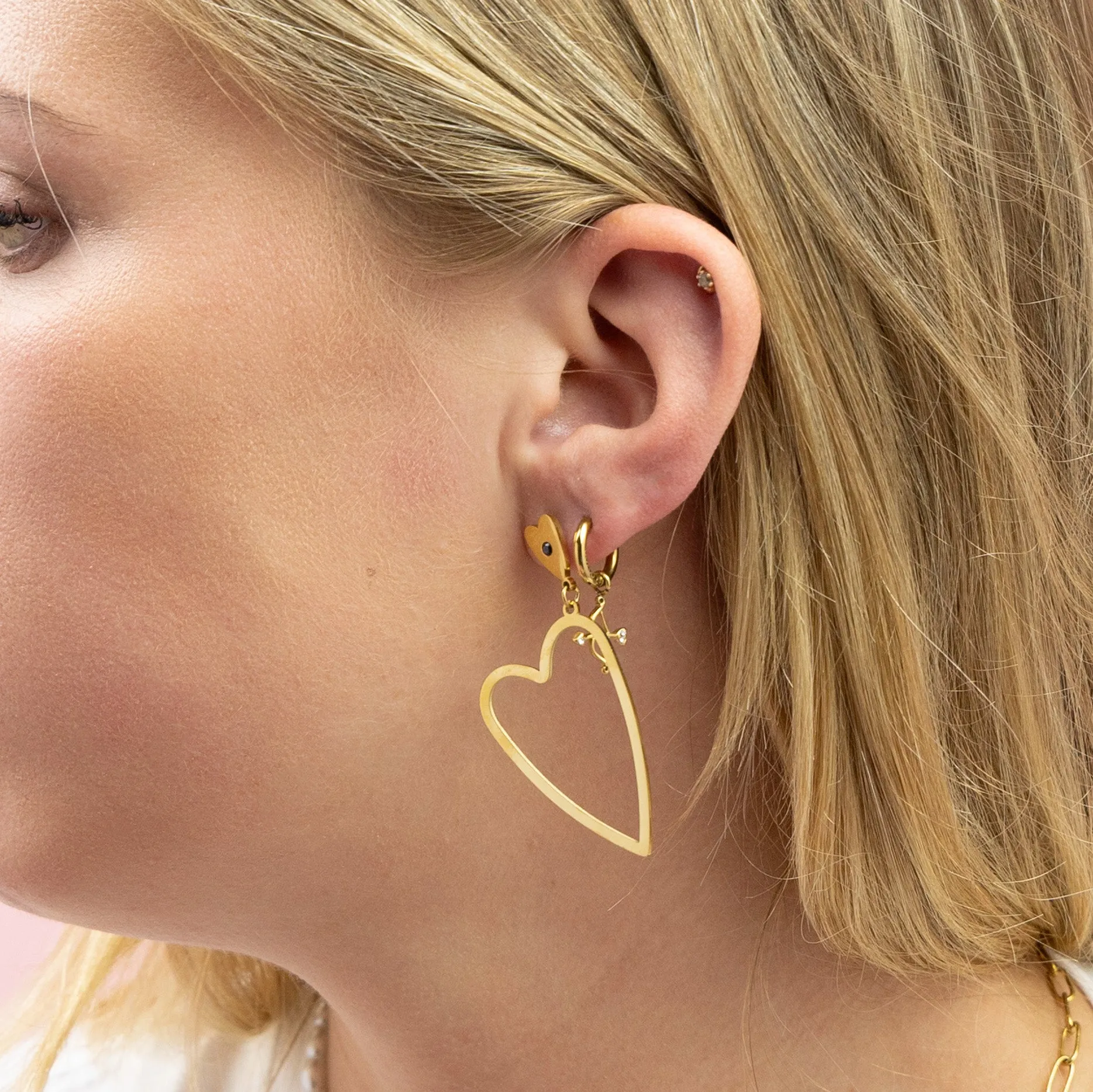 Gold coloured stud earrings with two hearts and a black rhinestone